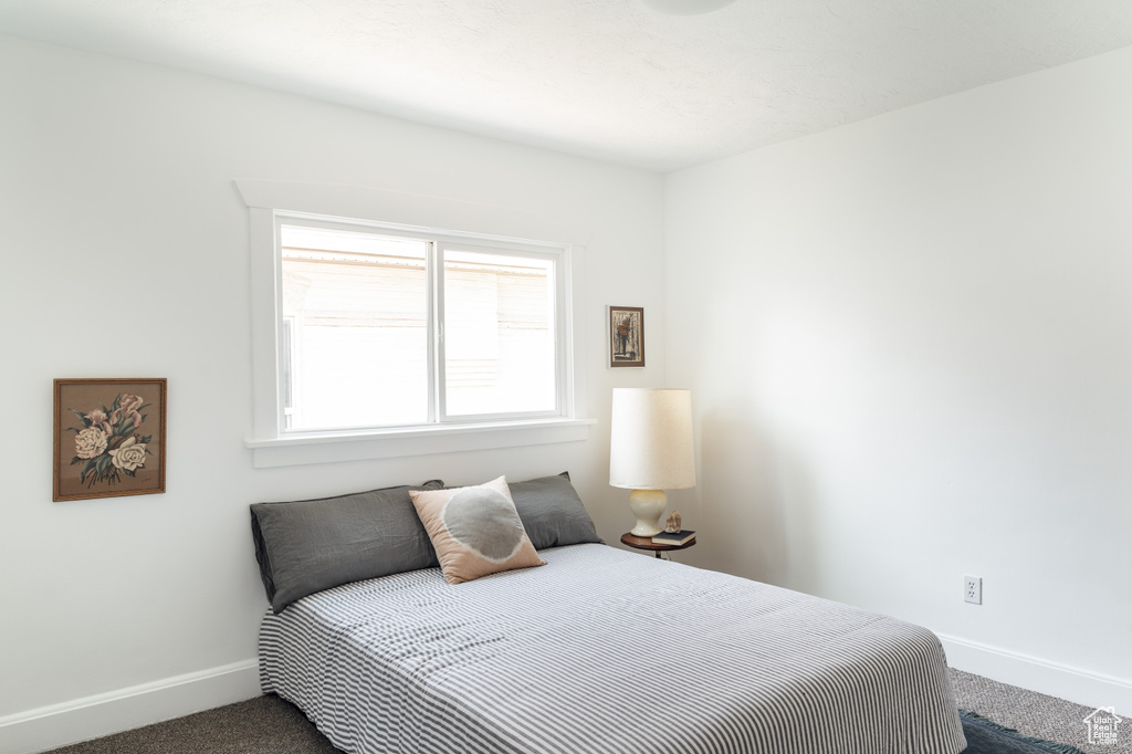 Bedroom with dark carpet and baseboards