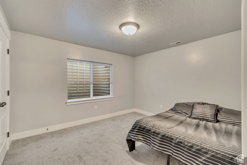 Bedroom featuring carpet flooring and a textured ceiling
