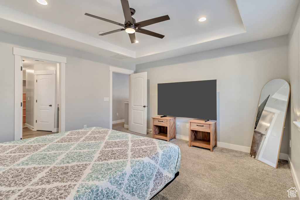 Carpeted bedroom featuring recessed lighting, a tray ceiling, and ceiling fan