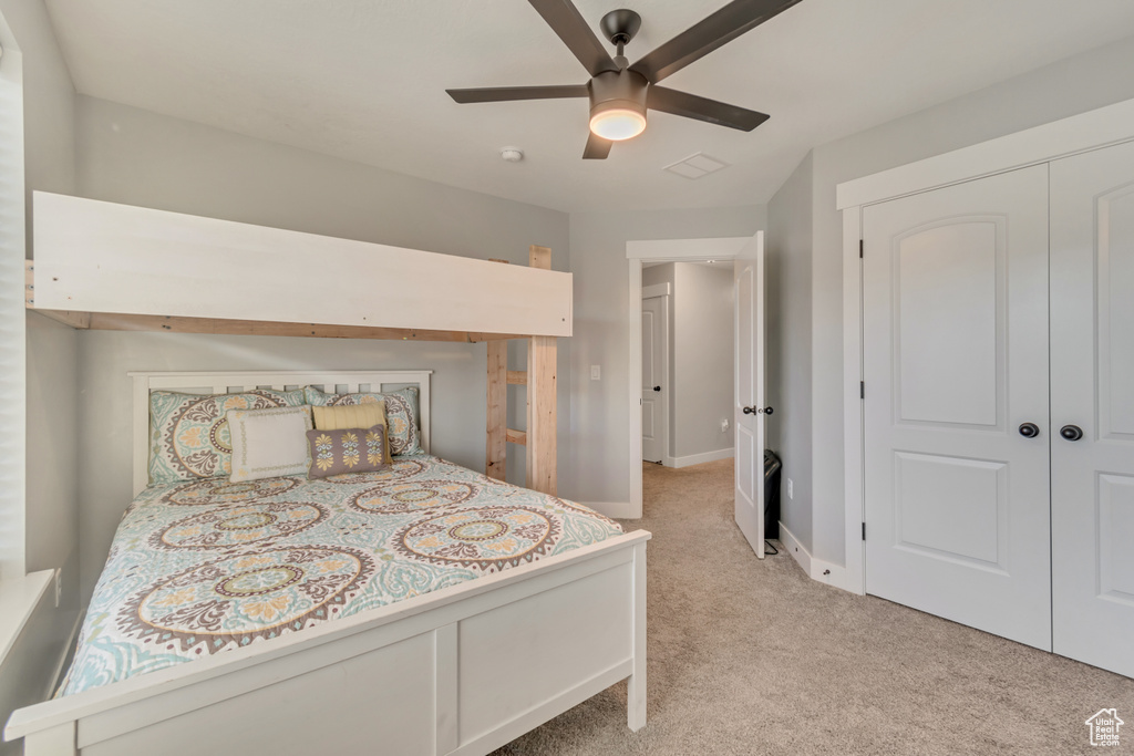Bedroom with light colored carpet, a ceiling fan, and a closet