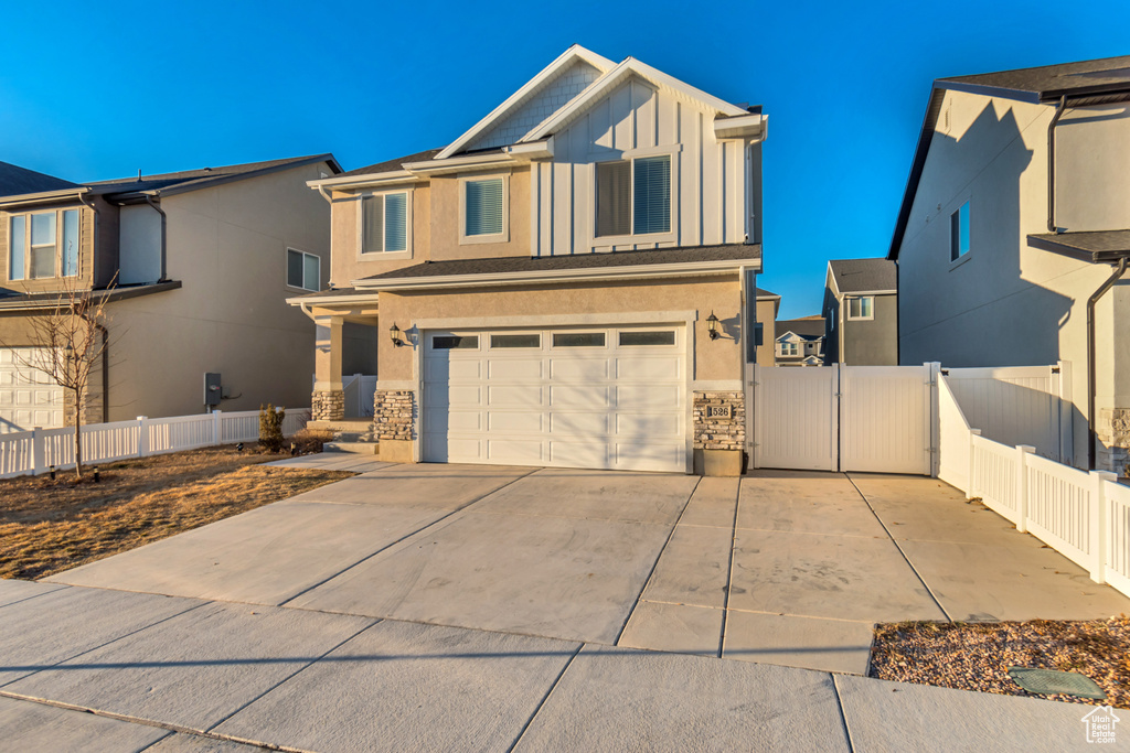 View of front facade with a garage, concrete driveway, stucco siding, and board and batten siding