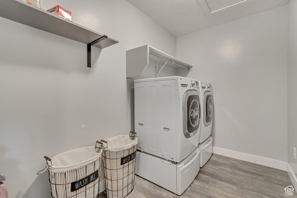 Laundry room featuring washing machine and clothes dryer and light wood-style flooring