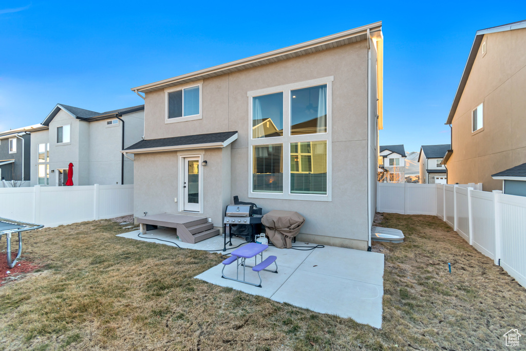 Rear view of property featuring stucco siding, a fenced backyard, a patio, a residential view, and a trampoline