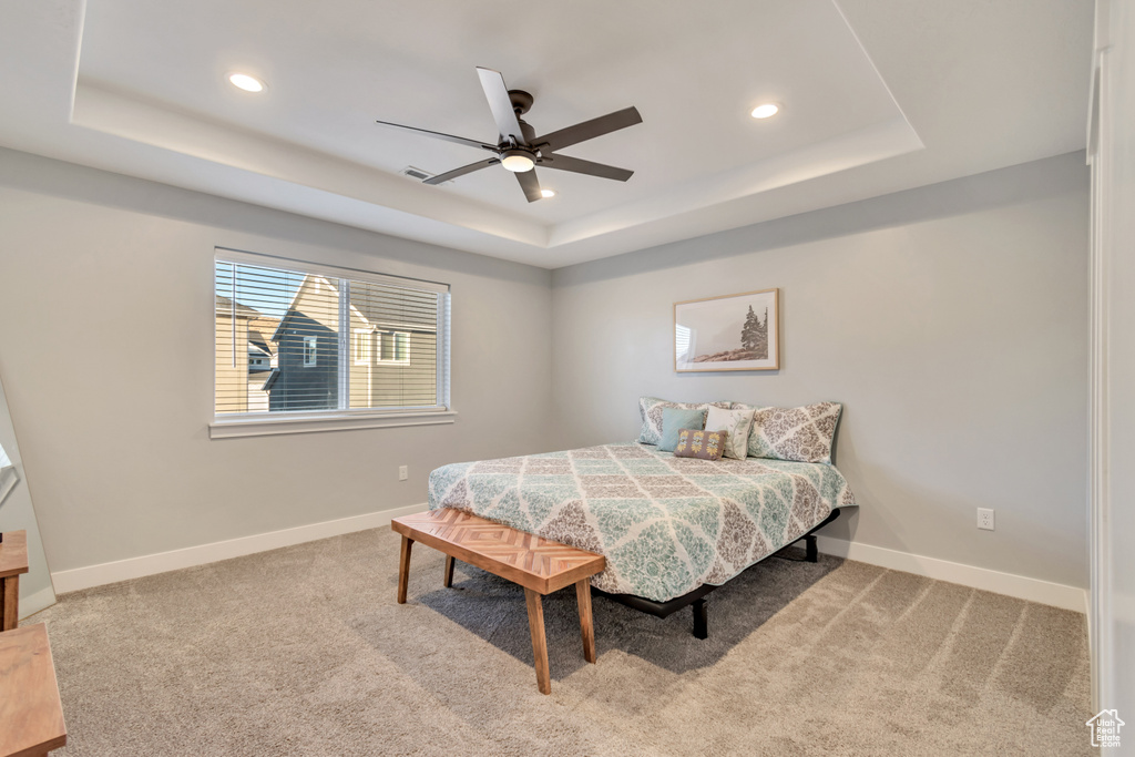 Carpeted bedroom with a tray ceiling, recessed lighting, and ceiling fan