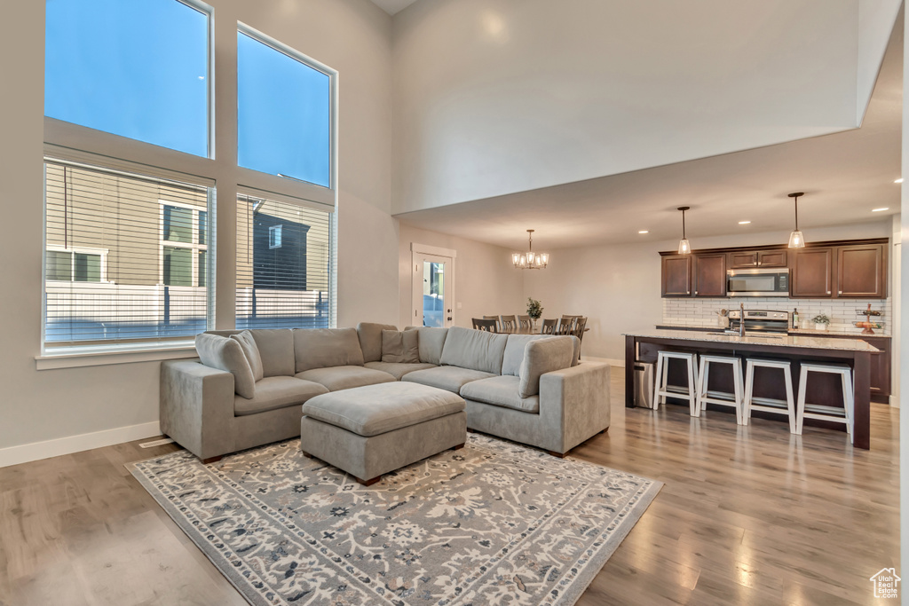 Living area with light wood finished floors, a chandelier, and recessed lighting