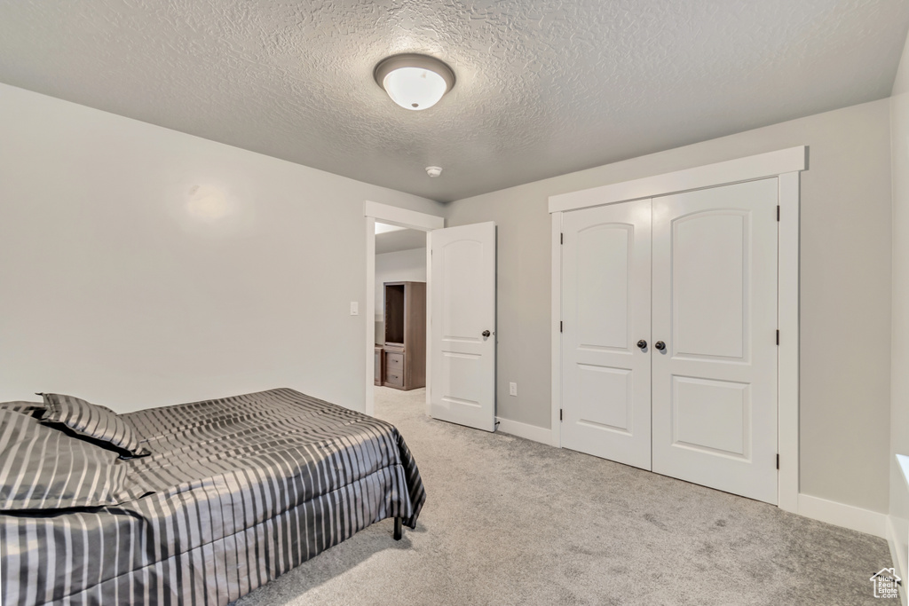 Bedroom featuring light carpet, a textured ceiling, and a closet