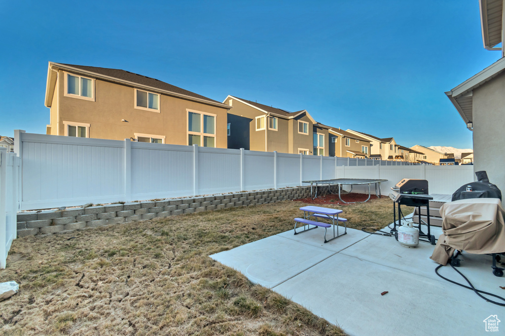 Fenced backyard with a trampoline, a residential view, and a patio area