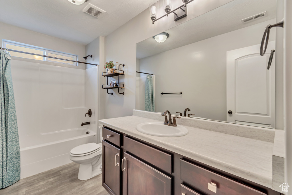 Bathroom featuring vanity, shower / bath combination with curtain, and wood finished floors