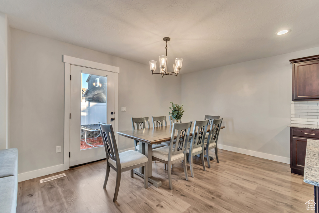 Dining space with light wood-style floors, a chandelier, and recessed lighting