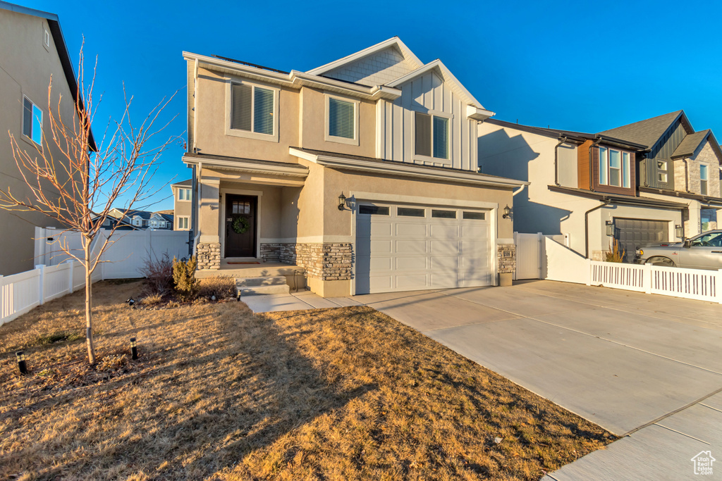 View of front of home with stone siding, an attached garage, stucco siding, concrete driveway, and a residential view
