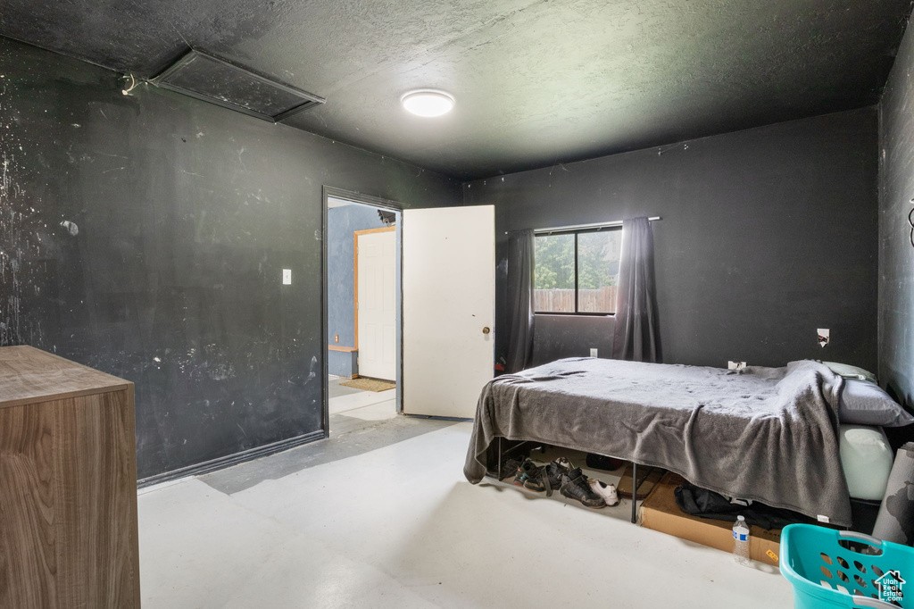 Bedroom featuring finished concrete floors and attic access
