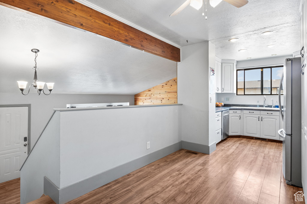Kitchen featuring appliances with stainless steel finishes, white cabinetry, a ceiling fan, a chandelier, and light wood-style floors