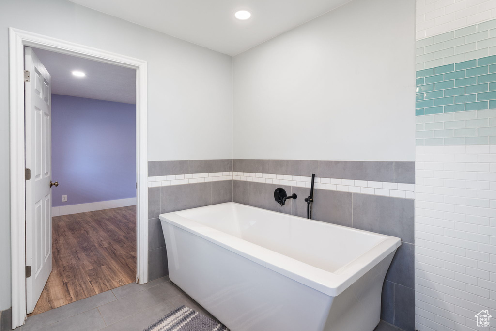 Full bath with tile walls, a soaking tub, tile patterned flooring, recessed lighting, and wainscoting