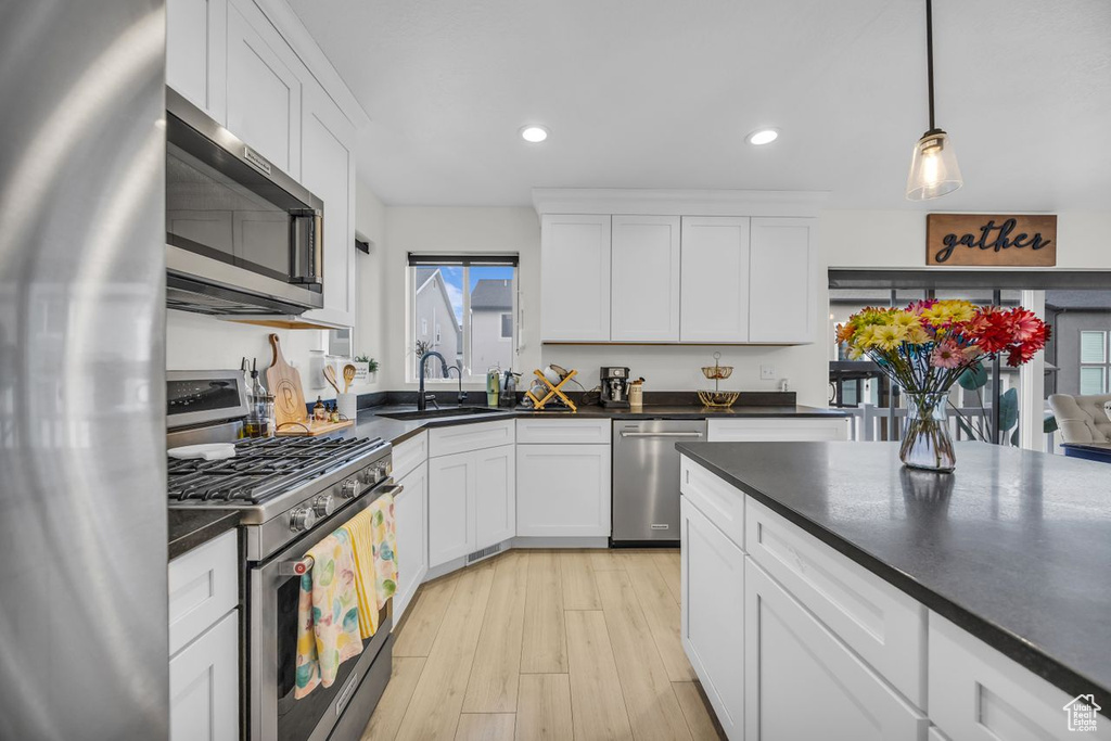 Kitchen featuring stainless steel appliances, dark countertops, recessed lighting, white cabinets, and light wood-style flooring