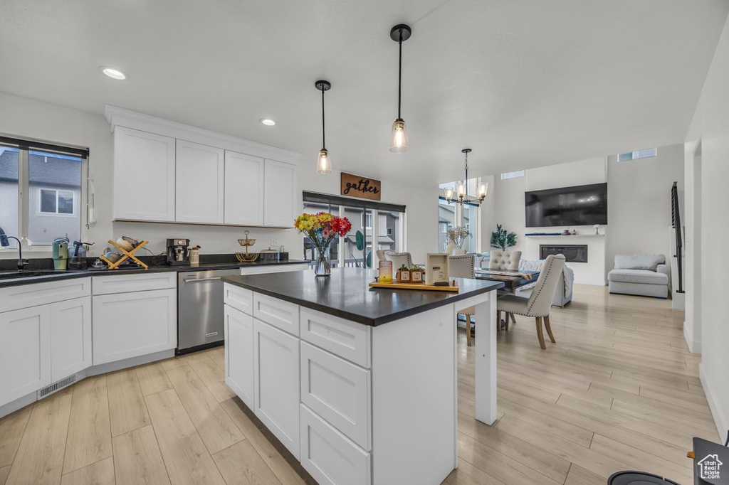 Kitchen featuring stainless steel dishwasher, dark countertops, a chandelier, white cabinets, and light wood finished floors