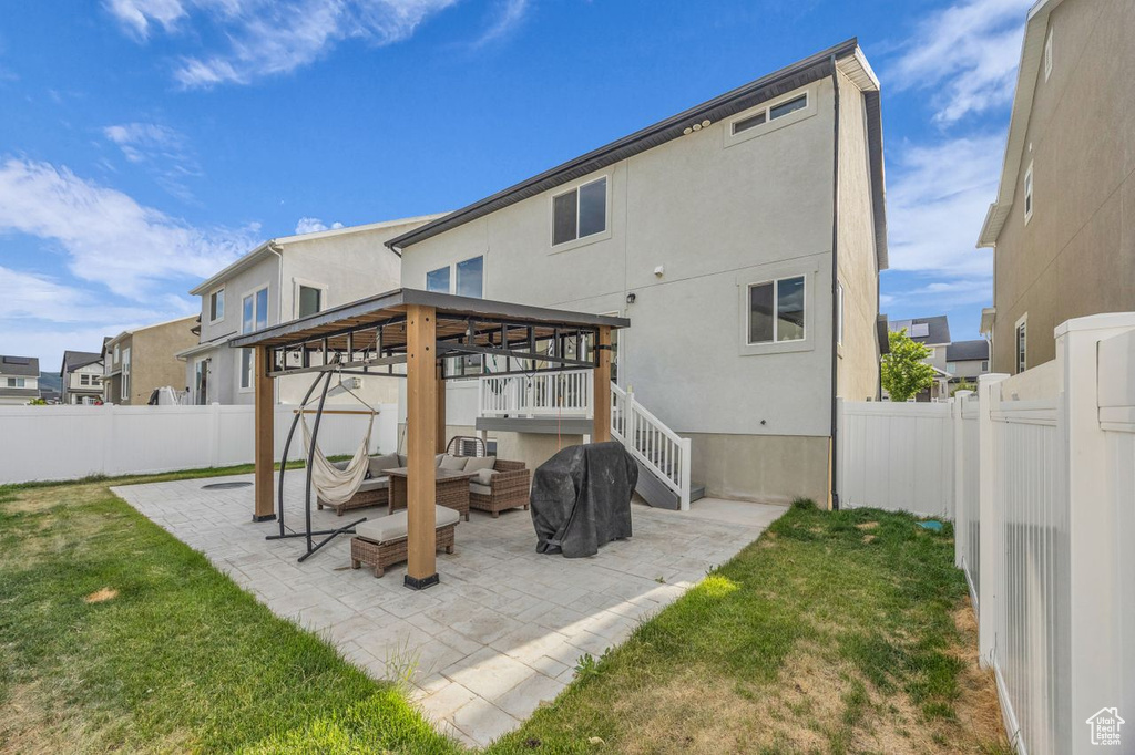 Back of property featuring outdoor lounge area, a fenced backyard, a patio, stucco siding, and a gazebo