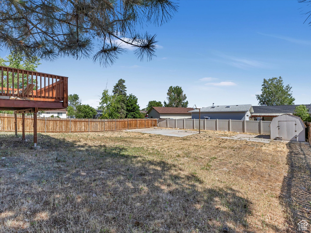 Fenced backyard featuring a shed and a wooden deck