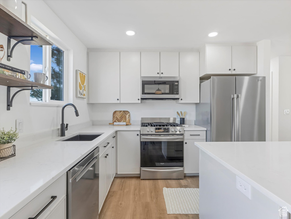 Kitchen featuring stainless steel appliances, light wood finished floors, white cabinetry, and recessed lighting