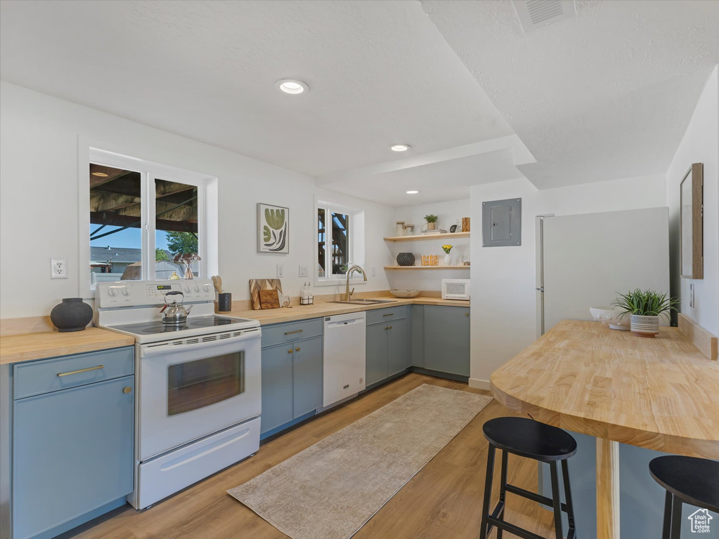 Kitchen featuring white appliances, open shelves, blue cabinets, light wood-style flooring, and recessed lighting