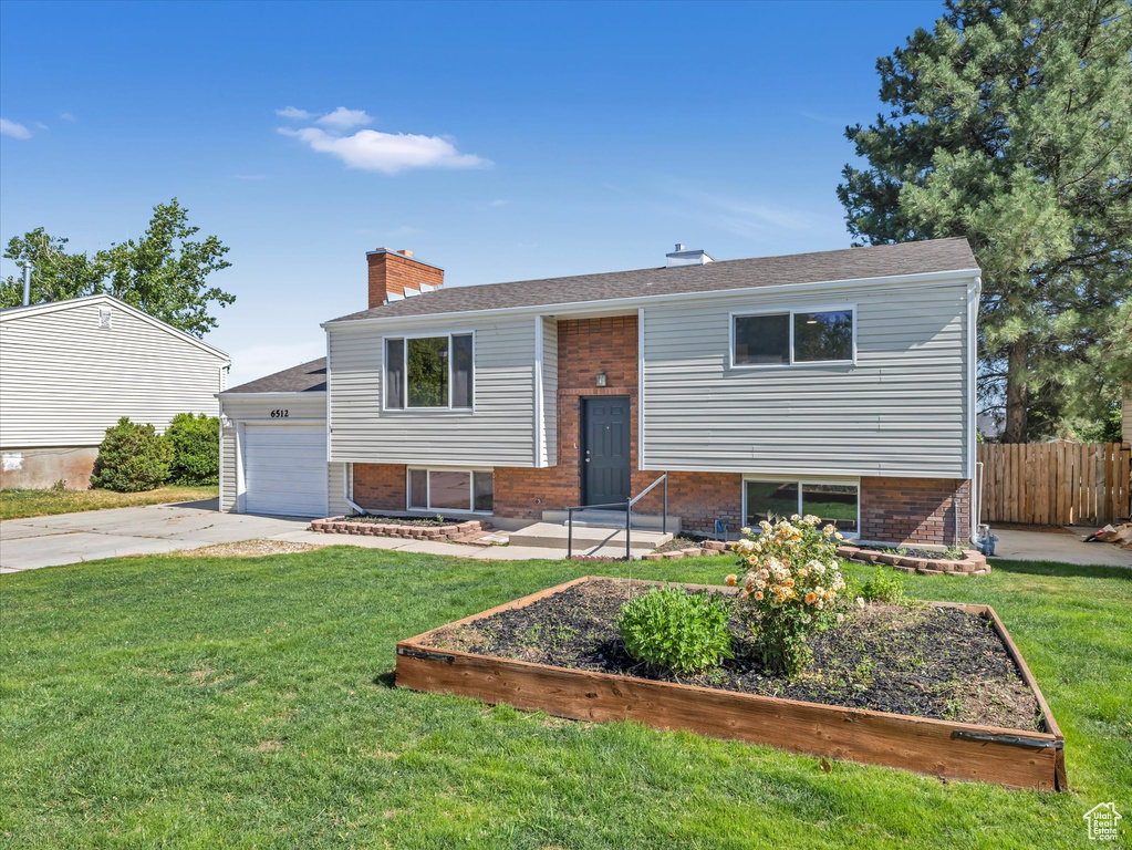 Split foyer home featuring brick siding, concrete driveway, a chimney, and a garage