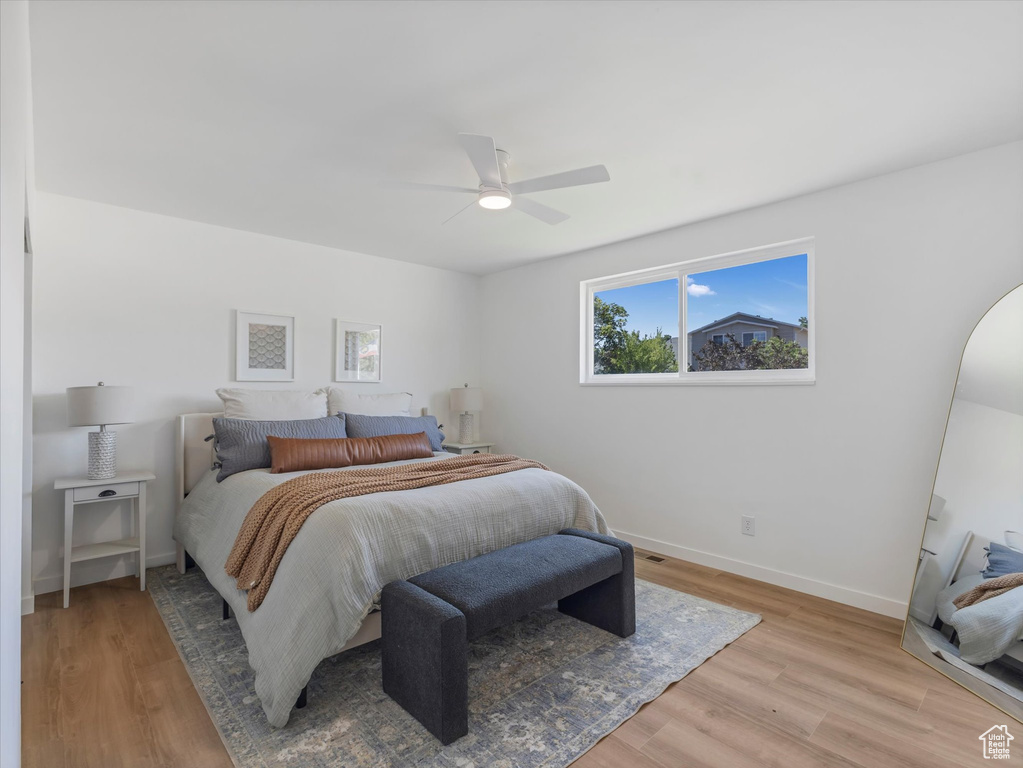 Bedroom with light wood finished floors, ceiling fan, and arched walkways