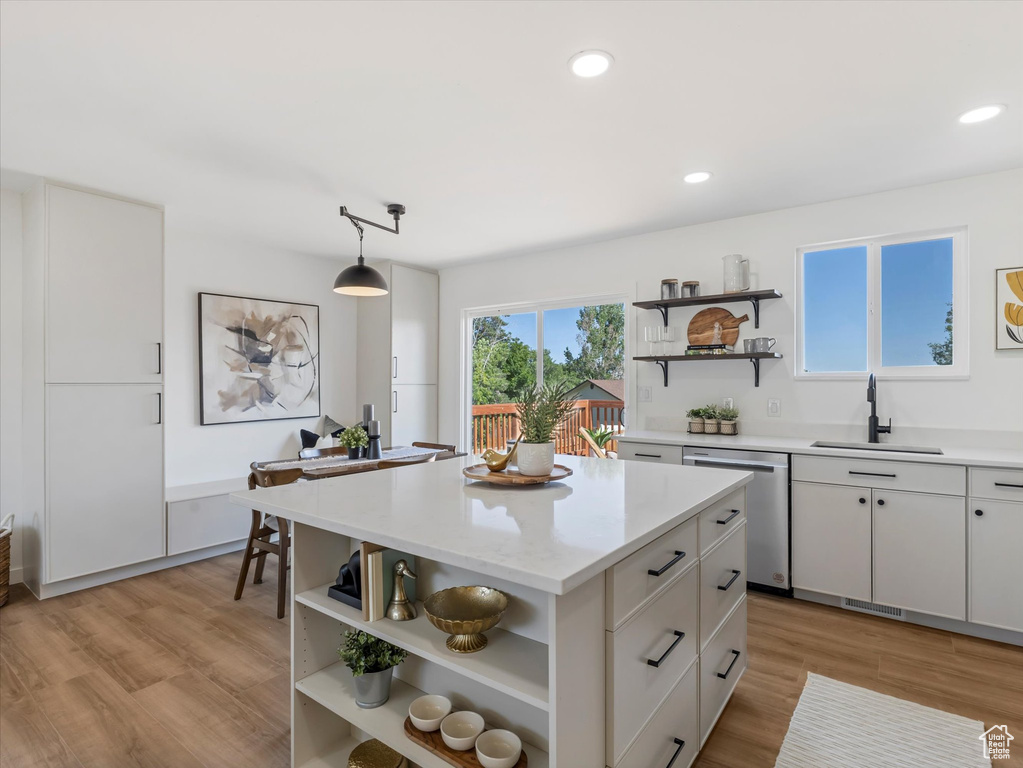 Kitchen with open shelves, stainless steel dishwasher, light wood-style flooring, recessed lighting, and a kitchen island