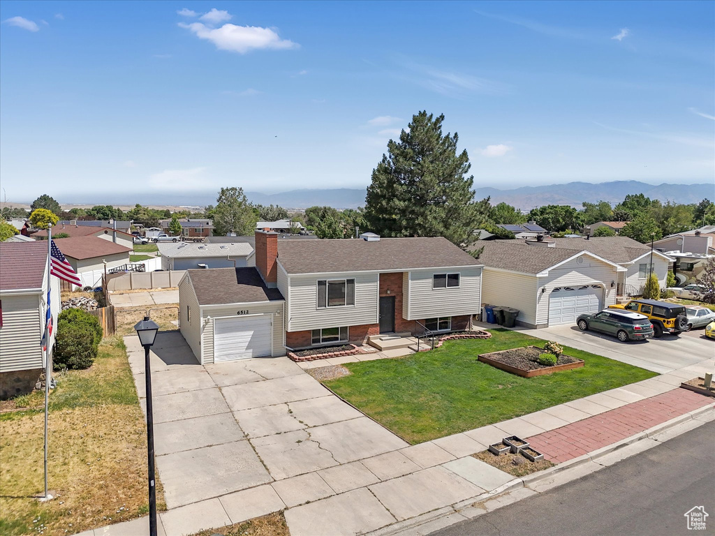 View of front of property featuring driveway, a residential view, a garage, a chimney, and a mountain view