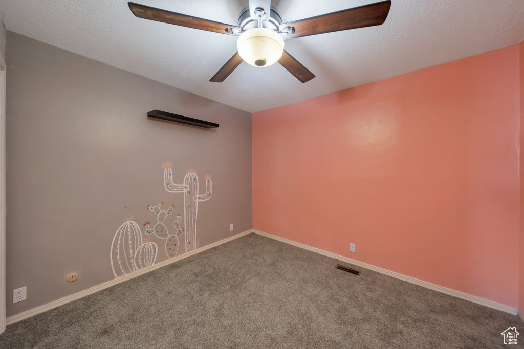Carpeted spare room featuring ceiling fan and baseboards