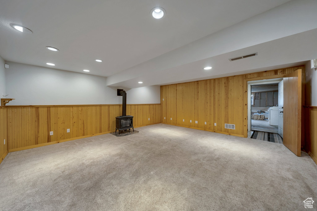 Basement featuring a wood stove, wainscoting, wooden walls, carpet, and recessed lighting