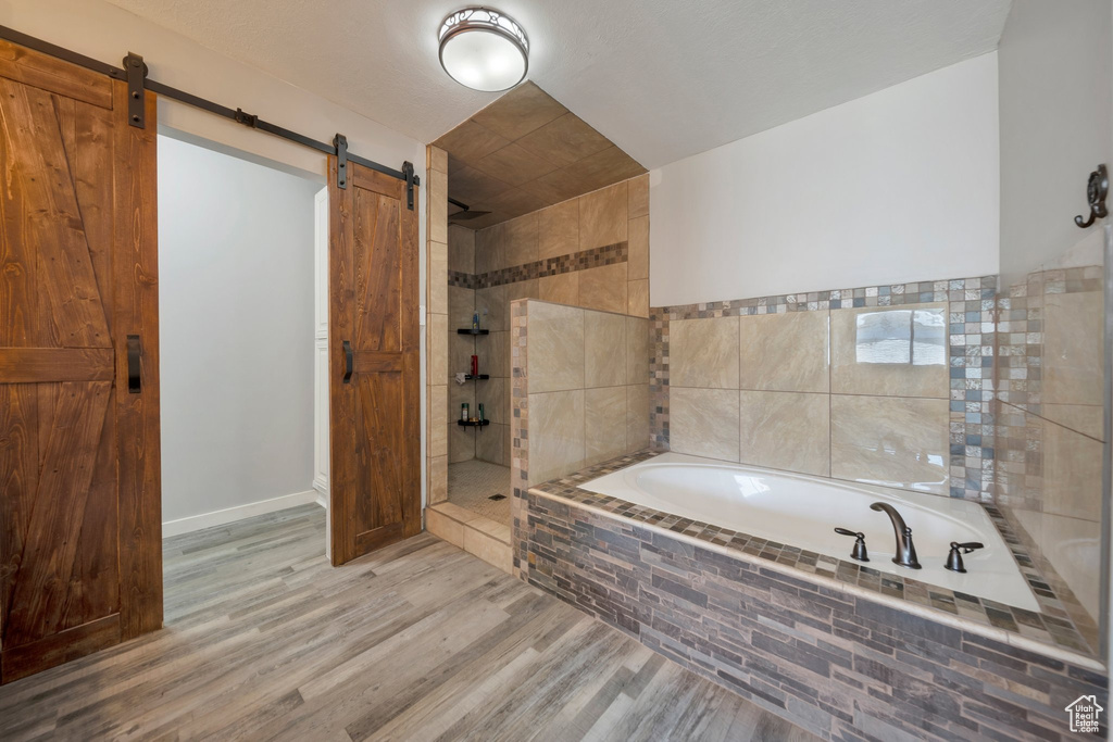 Full bathroom featuring a garden tub, walk in shower, and wood finished floors