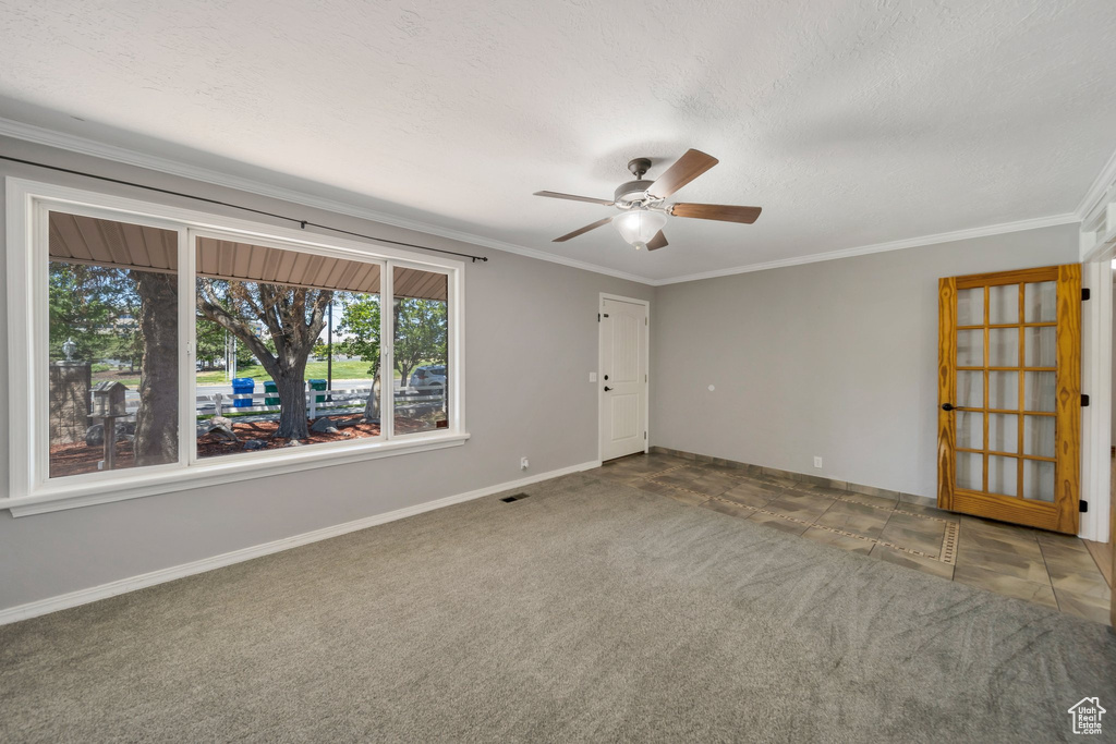 Empty room with ceiling fan, ornamental molding, carpet floors, and a textured ceiling