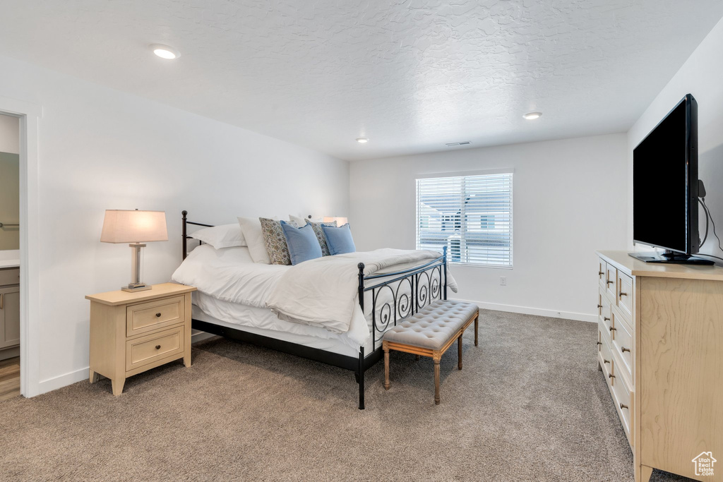 Bedroom with light colored carpet, a textured ceiling, and recessed lighting