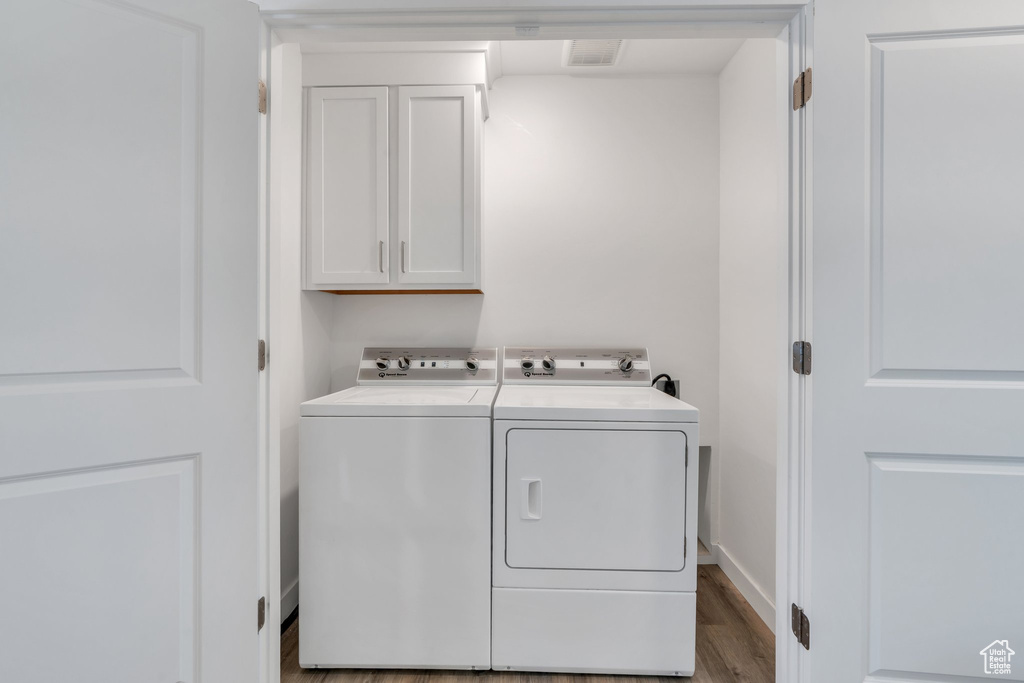 Laundry area with cabinet space, washing machine and clothes dryer, and wood finished floors