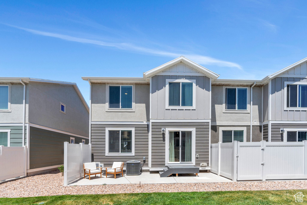 Back of property featuring a gate, board and batten siding, a patio, and an outdoor living space