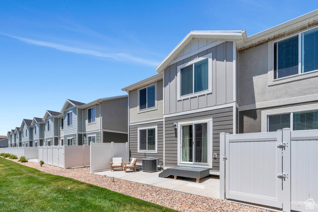 Rear view of property featuring a gate, board and batten siding, a patio, and a residential view