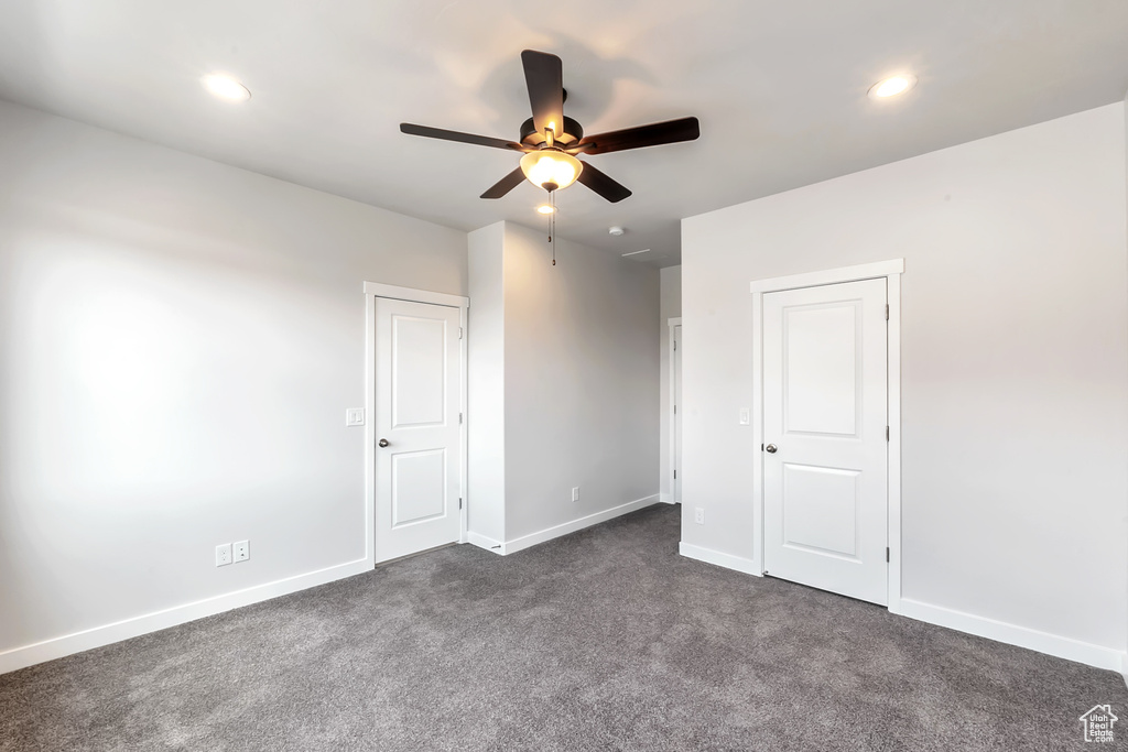 Unfurnished bedroom with dark colored carpet, recessed lighting, baseboards, and a ceiling fan