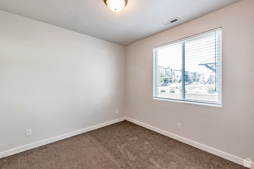 Unfurnished room featuring dark carpet and baseboards