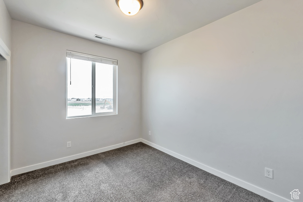 Unfurnished room featuring dark carpet and baseboards