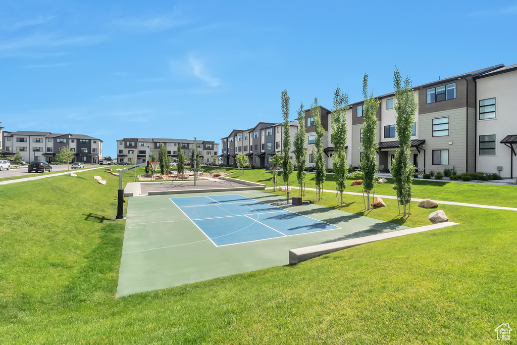 View of tennis court with a residential view and a yard