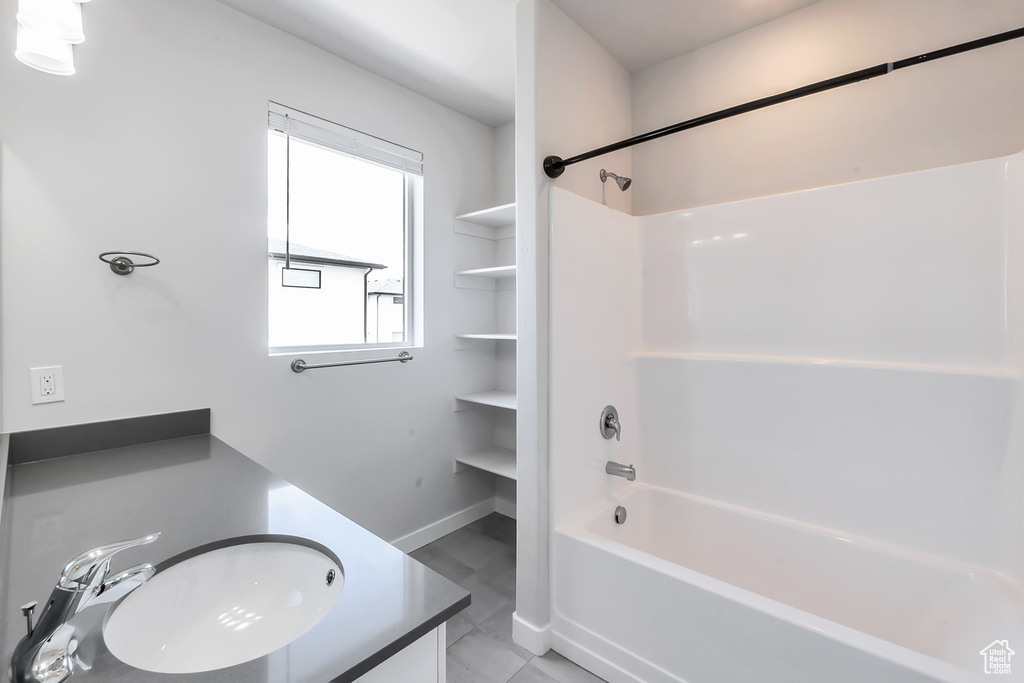 Bathroom with washtub / shower combination, tile patterned flooring, vanity, and baseboards