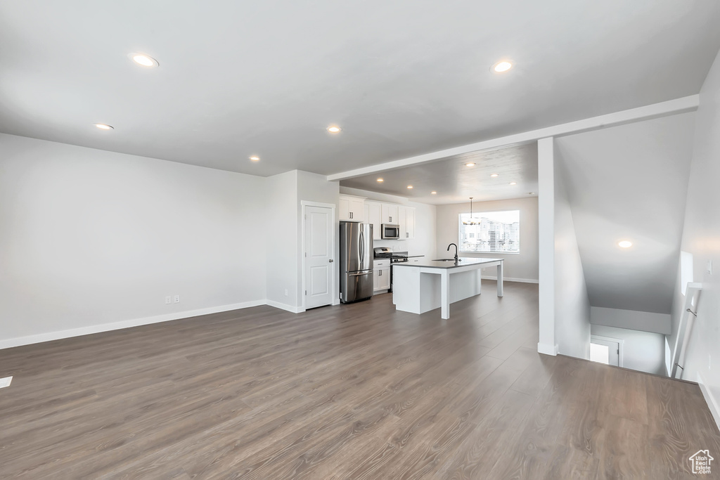 Unfurnished living room with recessed lighting, baseboards, dark wood-type flooring, and a sink