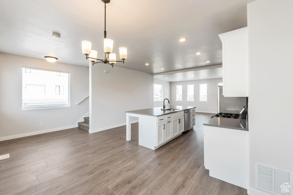 Kitchen featuring appliances with stainless steel finishes, a sink, a chandelier, white cabinetry, and recessed lighting