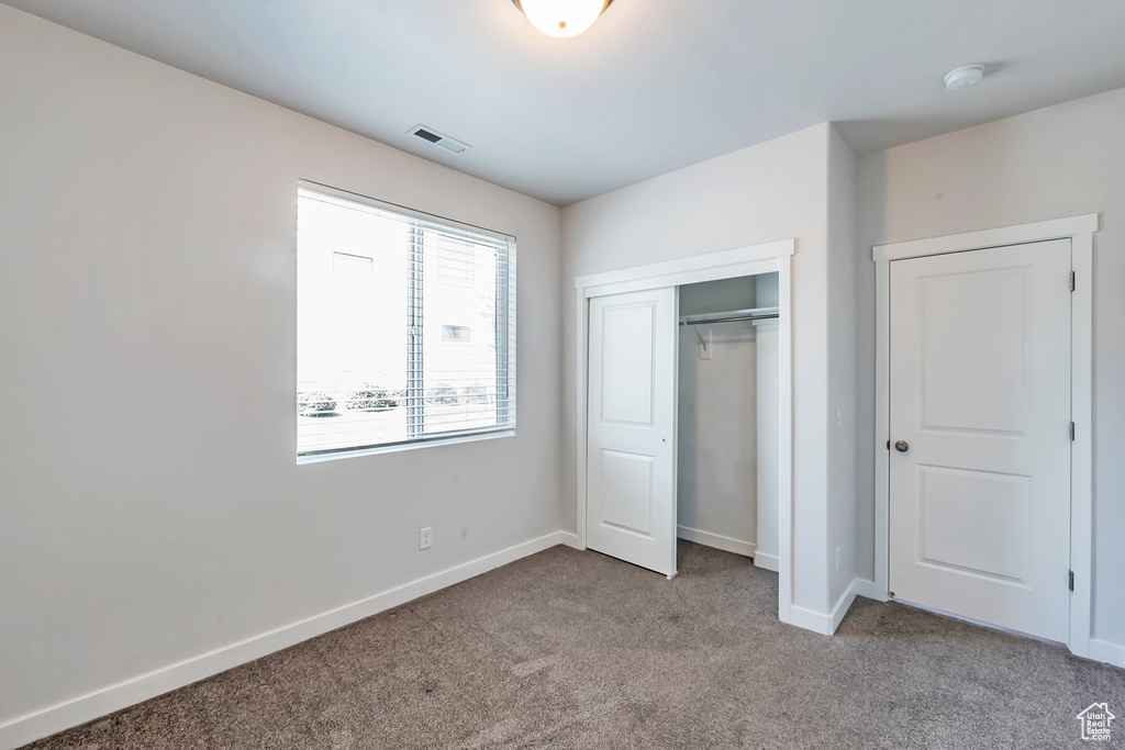 Unfurnished bedroom featuring carpet floors, baseboards, and a closet