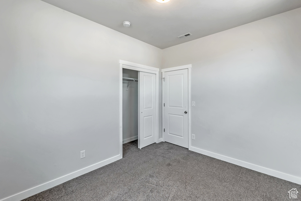 Unfurnished bedroom with dark colored carpet, baseboards, and a closet