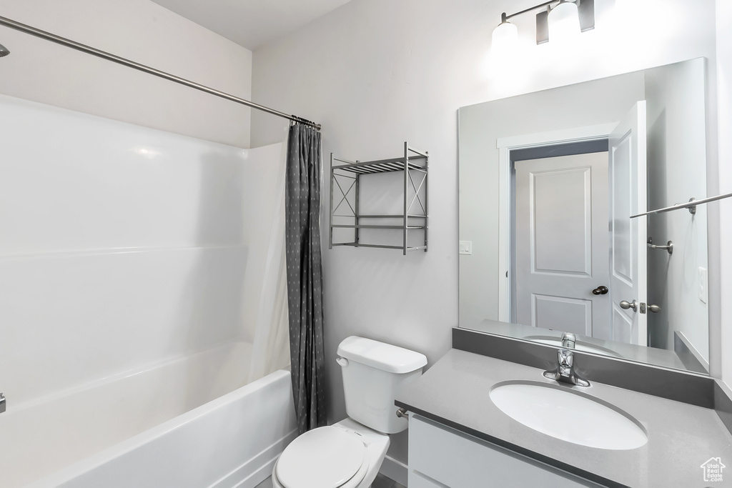 Bathroom with toilet, shower / tub combo, and vanity