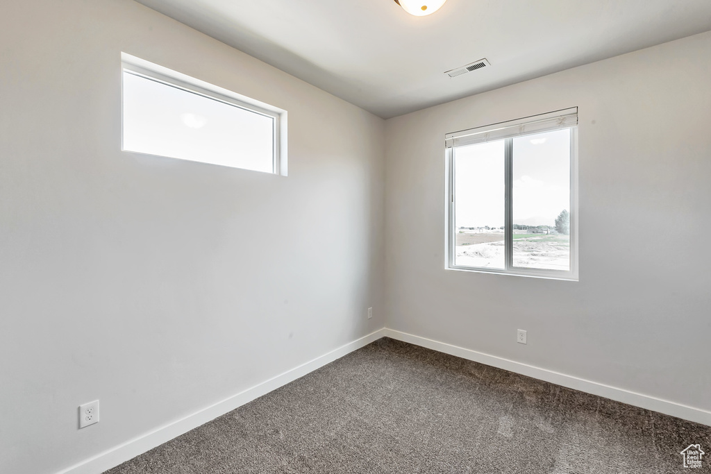 Spare room with dark colored carpet and baseboards