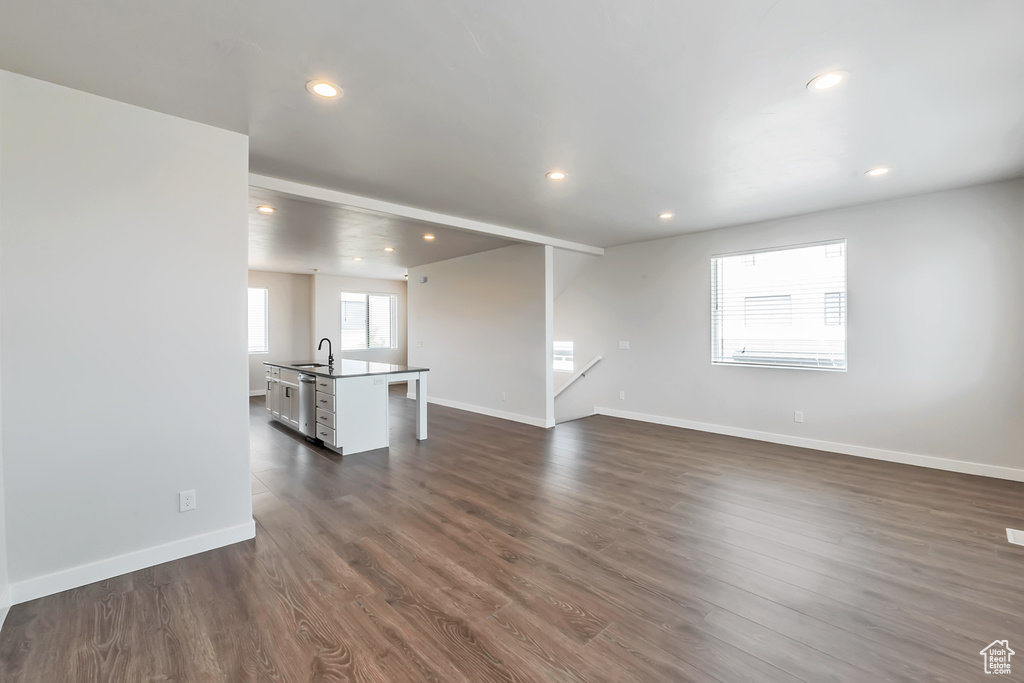 Unfurnished living room with a sink, recessed lighting, baseboards, and dark wood-type flooring