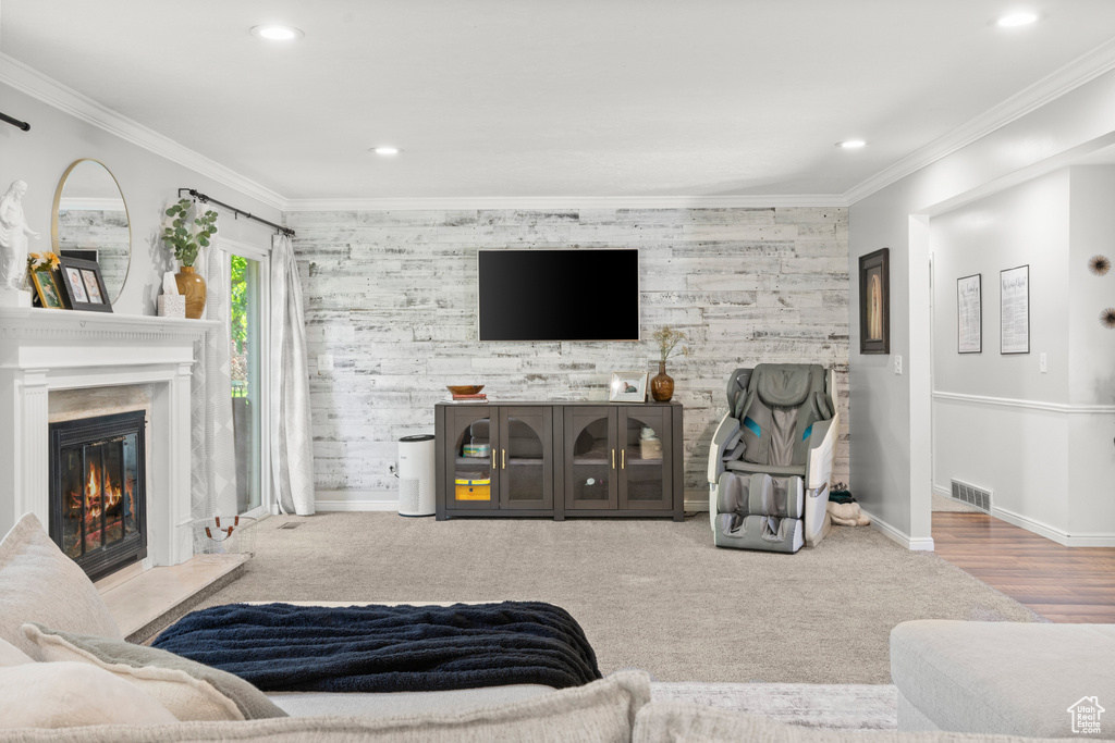 Living area with an accent wall, a glass covered fireplace, recessed lighting, and ornamental molding