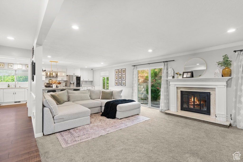 Living area with recessed lighting, crown molding, a glass covered fireplace, a chandelier, and wood finished floors