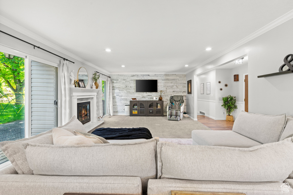 Living area with a glass covered fireplace, ornamental molding, and recessed lighting